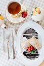 Pancakes with chocolate, strawberry and mint, with cup of tee