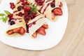 Pancakes with cranberries and strawberries on a plate. Pancakes with berries, strawberries and chocolate syrup.