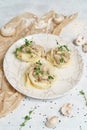 Pancakes or crepes stuffed with mushrooms with onion, garlic, herbs, cheese and cream on a white plate with sour cream Royalty Free Stock Photo