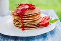 Pancakes with fresh strawberry and jam, near glass milk on white plate wooden background in garden or nature . Stack of th Royalty Free Stock Photo