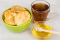 Pancakes in green bowl, honey, wooden stick and tea Royalty Free Stock Photo