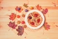 Pancakes with homemade plum  jam on white plate, fresh plums and autumn maple leaves on wooden background.  Toned image Royalty Free Stock Photo