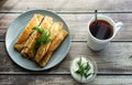 Pancakes with meat on a gray plate, sour cream, garnished with dill. Tea in a white cup. wooden background Royalty Free Stock Photo