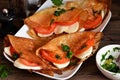 Pancakes with mozzarella and tomatoes with pesto on the kitchen table. Pancakes with caprese Royalty Free Stock Photo