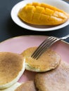 Pancakes on a pink plate. mango slice