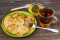 Pancakes in plate, bowl with honey and cup of tea Royalty Free Stock Photo