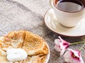 Pancakes, a plate with sour cream and a cup with red tea on a table Royalty Free Stock Photo