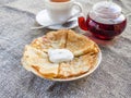 Pancakes on a plate with sour cream and teapot with tea Royalty Free Stock Photo