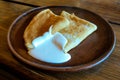 Pancakes on a plate with sour cream. Traditional for the Russian pancake week. Dark background.
