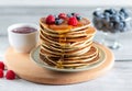 Pancakes with raspberries, blueberries, jam and trickle of honey on wooden board