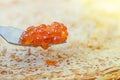 Pancakes with red caviar on a plate. Next to pancakes is a spoon with caviar. Light background. Close-up. Royalty Free Stock Photo