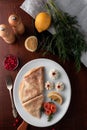 Pancakes with red fish, lemon and cranberries on a white plate, table served in restaurant in rustic style, concept of russian