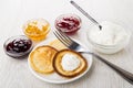 Pancakes in saucer with cottage cheese, spoon, bowls with jams