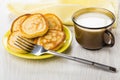 Pancakes in saucer, cup with milk, fork, yellow napkin Royalty Free Stock Photo