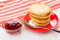 Pancakes on saucer, napkin, bowl with strawberry jam, spoon