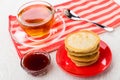 Pancakes on saucer, tea, spoon on napkin, bowl with jam
