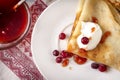 Pancakes with sour cream, berries, cranberries and jam on a plate, tea, jam on a towel with a red pattern on a white Royalty Free Stock Photo