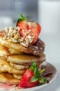 Pancakes stacked with bananas, strawberries and nuts, topped with chocolate and strawberry sauce Royalty Free Stock Photo