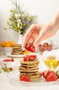 Pancakes with strawberries, delicious breakfast. Woman decorates a stack of pancakes with strawberries. vertical food photo Royalty Free Stock Photo