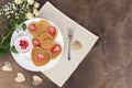 Pancakes with strawberry cream and berry slices on a white plate on a wooden table