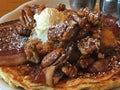 Pancakes topped with fried chicken, bacon, pecans, and whipped butter