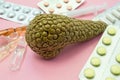 Pancreas treatment concept photo. Figure of pancreas surrounded by pills, medications, medicine vials with syringe, symbolizing tr Royalty Free Stock Photo