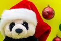 Panda Bear plush toy with Red Christmas Santa Hat surrounded by Colorful Vintage Ornaments on bright yellow background. Winter Royalty Free Stock Photo