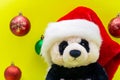 Panda Bear plush toy with Red Christmas Santa Hat surrounded by Colorful Vintage Ornaments on bright yellow background. Winter Royalty Free Stock Photo