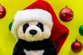 Panda Bear plush toy with Red Christmas Santa Hat surrounded by Colorful Vintage Ornaments on bright yellow background. Winter Royalty Free Stock Photo