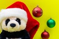 Panda Bear plush toy with Red Christmas Santa Hat surrounded by Colorful Vintage Ornaments on bright yellow background. Winter Royalty Free Stock Photo