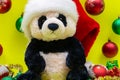 Panda Bear plush toy with Red Christmas Santa Hat surrounded by Tinsel Garland and Vintage Ornaments on bright yellow Royalty Free Stock Photo