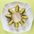 Pandan moon cake cut into eighths in white plate, green background. Close up. Royalty Free Stock Photo