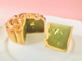 Pandan seeds moon cake with a portion cutout on pink background. Royalty Free Stock Photo