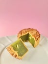 Pandan seeds moon cake with a portion cutout on pink background. vertical. Royalty Free Stock Photo