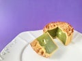 Pandan seeds moon cake with a portion cutout on purple background. Royalty Free Stock Photo