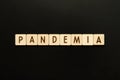 PANDEMIA - word from wooden blocks with letters. Top view on black background.