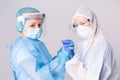 Pandemic. Tired doctors in covid-19 protective gear hold hands in support of a dire situation. Gray background.