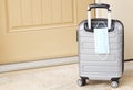 Pandemic travel seen in tan door, gray suitcase, and face mask