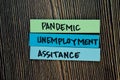 Pandemic Unemployemnt Assitance write on sticky notes isolated on Wooden Table Royalty Free Stock Photo