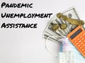 Pandemic Unemployment Assistance written on white background with calculator,hand sanitizer,face mask,fake money and coins. Royalty Free Stock Photo