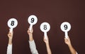 Panel of judges holding different score signs on brown background, closeup