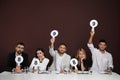 Panel of judges holding different score signs at table on brown background