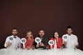 Panel of judges holding signs with highest score at table on brown background