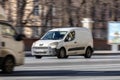 Panel van Peugeot Partner driving in the city street. White minivan in motion, front side view