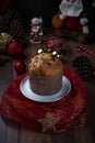 Panettone on a white plate wrapped in red tulle on a wooden table with Christmas decoration spread around it Royalty Free Stock Photo