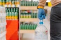 Panic shopping during coronavirus pandemic. Unrecognizable man shopper wears rubber gloves, carries bottle of drinking water,