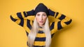 Panicking young woman stare to you, model wearing woolen cap and sweater, on yellow background. Mistake. Bad news