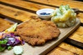 Paniertes HaÃËhnchen Schnitzel auf einem Holzbrett mit Kartoffelsalat, KrÃÂ¤uterbutter, Beilagensalat, Zitrone und Preiselbeeren in Royalty Free Stock Photo