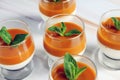 Panna cotta dessert with mango puree with mint leaves in a glass on a marble table