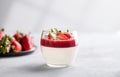 Panna cotta with strawberry and cream in glass with fresh berries on a light background close up with shadow